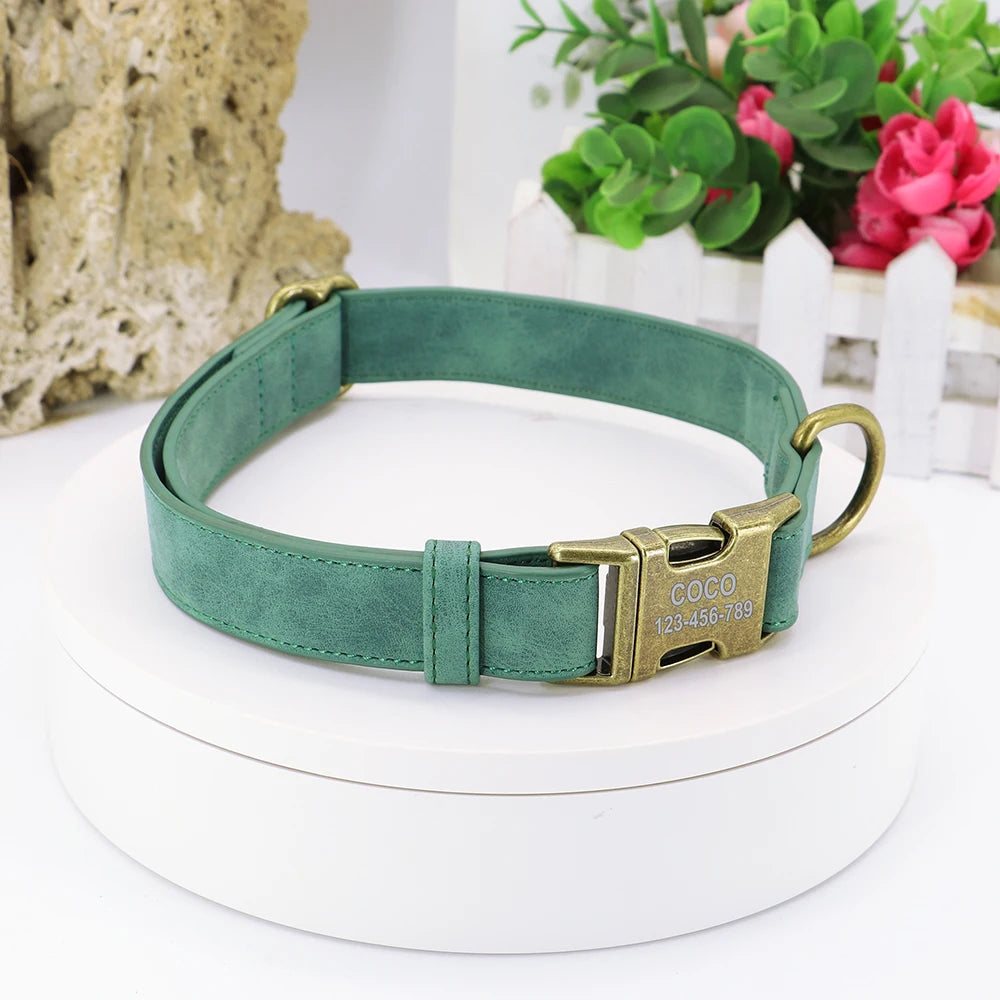 Custom green leather dog collar with engraved brass nameplate on a white display stand, next to faux plants and a picket fence decor. Ideal for pet safety and style.