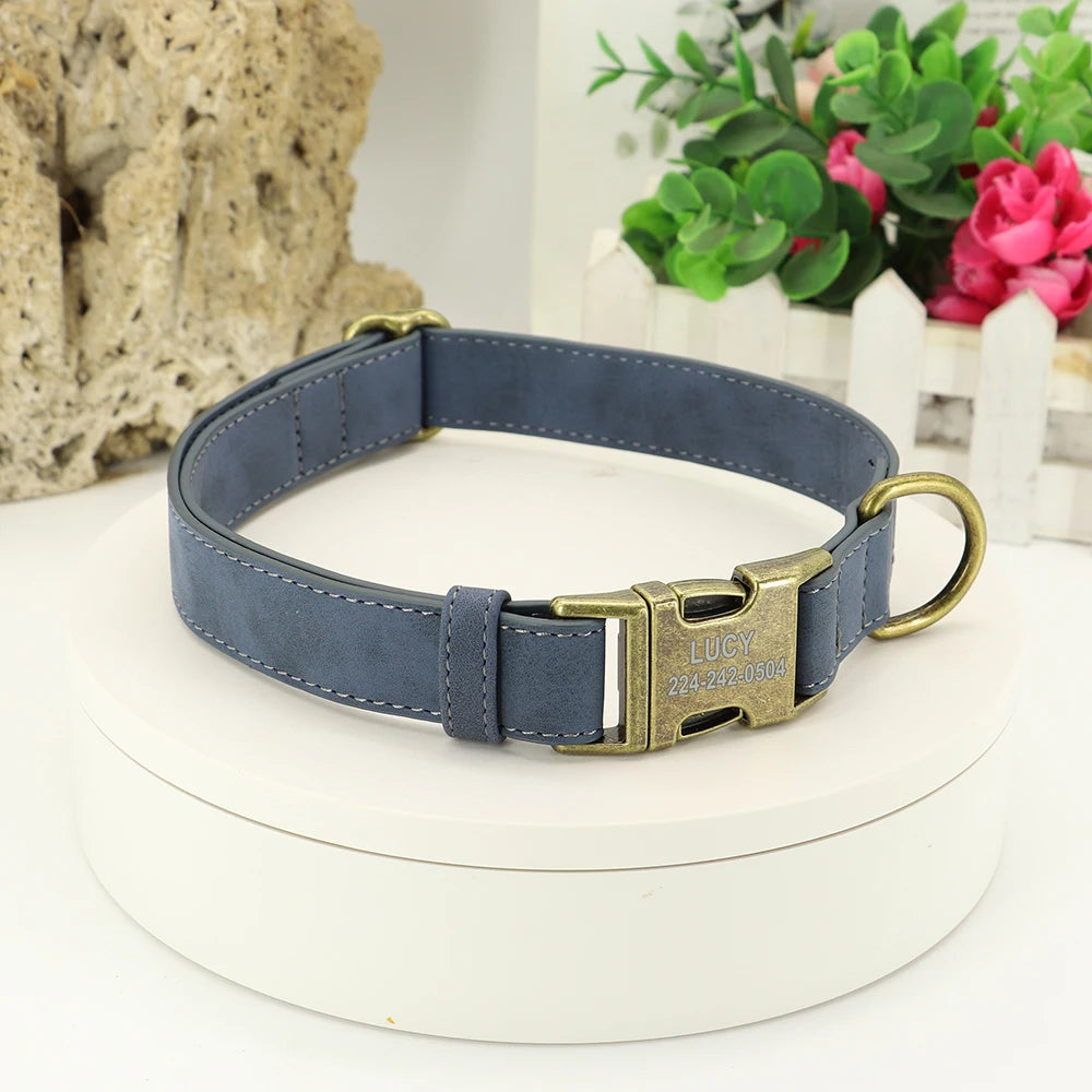 Elegant navy blue personalized dog collar with gold-tone hardware and custom engraved ID tag, showcased on a white display stand with a natural backdrop. Ideal for stylish pet safety.